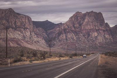 Road by mountains against sky