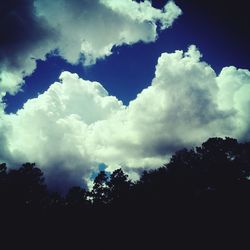 Low angle view of silhouette trees against cloudy sky