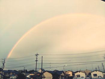 Rainbow over buildings in city against sky