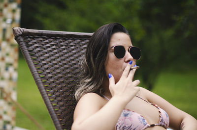 Portrait of young woman holding sunglasses