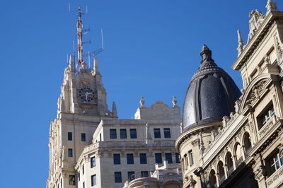 Low angle view of clock tower against clear blue sky