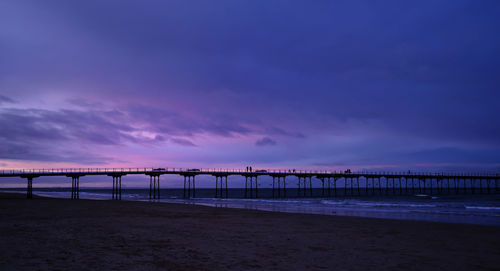 Bridge over sea against sky at sunset