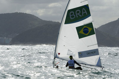 Man on boat in sea against mountains