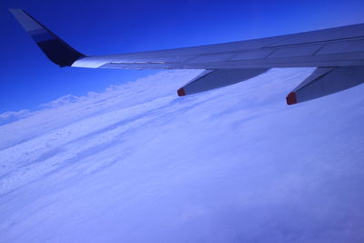 Snow covered landscape against blue sky
