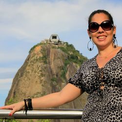 Portrait of young woman wearing sunglasses standing against sky