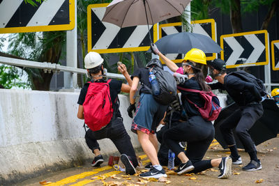 Rear view of people walking on yellow umbrella in city