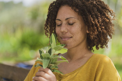 Portrait of woman holding plant outdoors