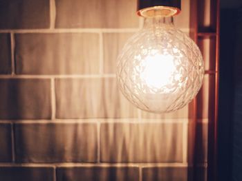 Close-up of illuminated lamp hanging on wall at home