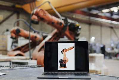 Laptop with robotic arm photograph at desk in industry