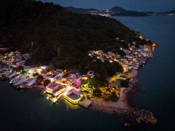 High angle view of illuminated city by sea