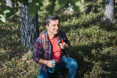 Man with backpack hiking in forest, actively spending summer vacation close to nature