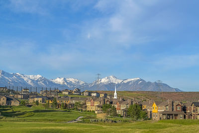 Houses on field by mountain against sky