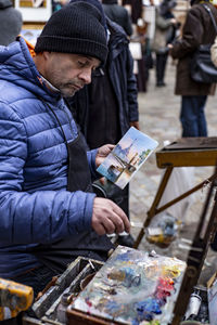 Painter holding painting while working on street
