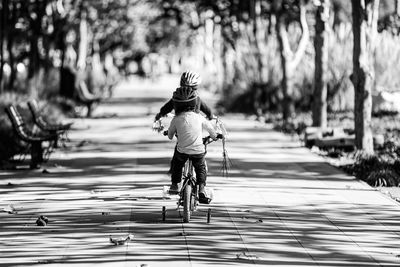 Rear view of boys cycling on footpath