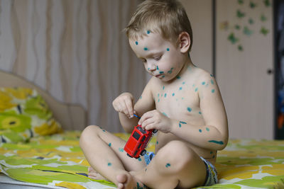 Shirtless boy playing with toy at home