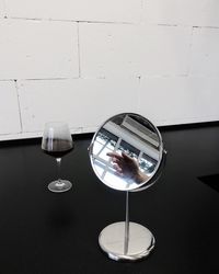 Close-up of wine glass by mirror on table against wall