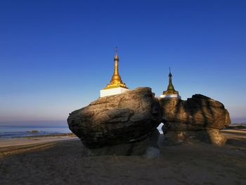 View of temple on beach against clear sky