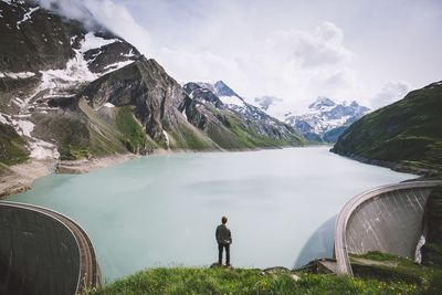 High angle view of man standing on cliff against kaprun dam during winter