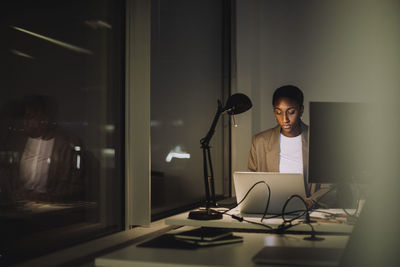 Ambitious businesswoman using laptop while working last minute in office