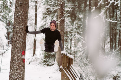 Woman standing by tree in forest during winter
