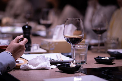 Midsection of man holding wine glass on table