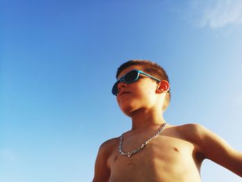 Low angle view of shirtless boy wearing sunglasses against clear sky