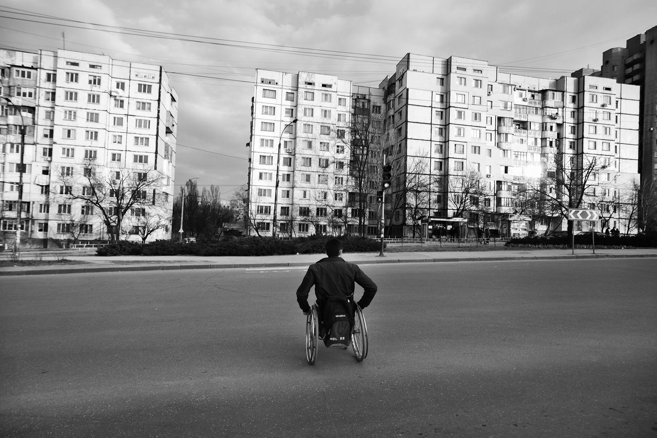 REAR VIEW OF A MAN WALKING ON ROAD