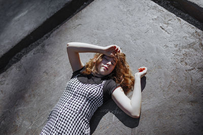 Teenage girl lying on footpath during sunny day