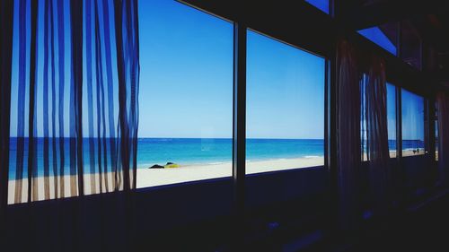 Scenic view of sea against blue sky seen through window