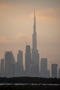 Modern buildings in city against sky during sunset