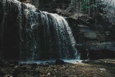 Man standing against waterfall in forest