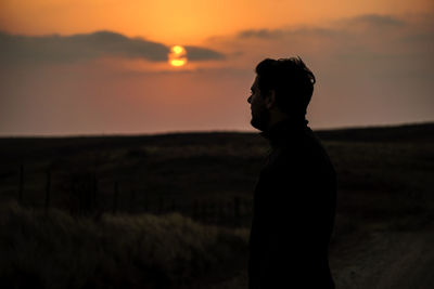 Side view of woman standing at sunset