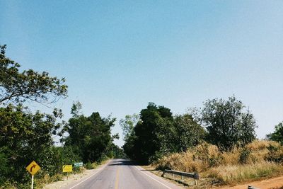 Road amidst trees against clear sky