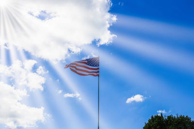 American flag waving in a cloudy sky and sunbeams. usa flag flies