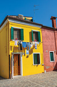 Windows on colorful house and clothes hanging on in burano, a little town full of canals in italy.