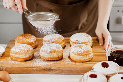 Woman prepares fresh donuts with jam in home kitchen. cooking jewish hanukkah sufganiyot.