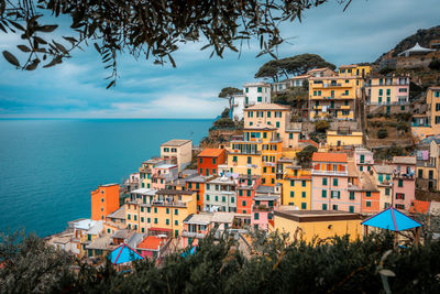 Buildings by sea against sky