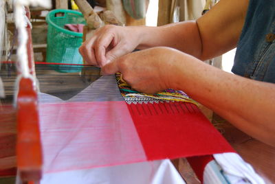 Midsection of woman working with loom in workshop