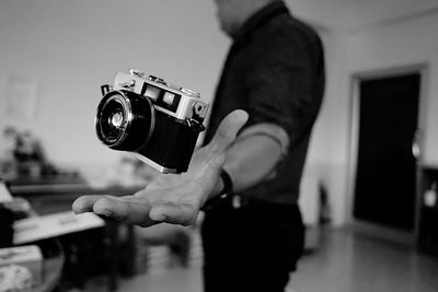 Midsection of man catching camera at home