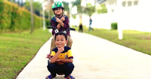 Portrait of brothers on footpath at public park