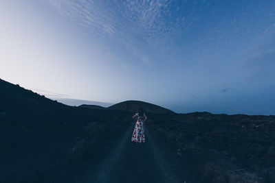 Rear view of man walking on mountain against sky