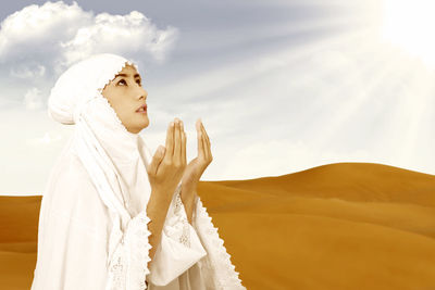 Woman standing on cross against sky