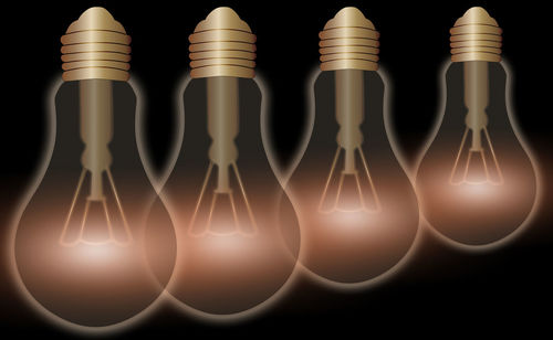 Close-up of illuminated light bulb against black background