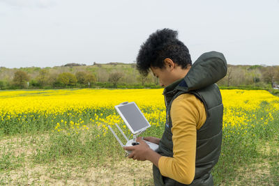 Rear view of man using mobile phone in field