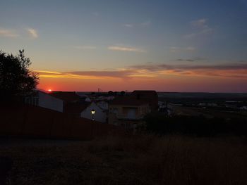 Houses on field against sky during sunset