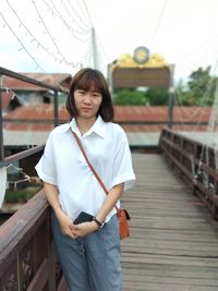 Portrait of young woman standing on footbridge