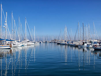 Sailboats moored on sea against clear blue sky