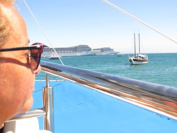 Rear view of woman contemplating
 ships and sailboat in sunny morning  in blue sea against clear sky