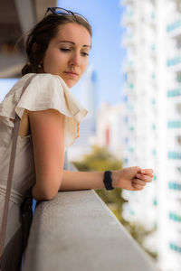 Thoughtful woman standing by retaining wall at balcony