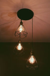 Illuminated light bulb hanging on wall at home